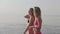 Two young girls in bikinis on the beach walk