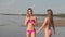 Two young girls in bikinis on the beach walk