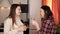 Two young girls chatting in the kitchen and drinking orange juice while dinner is being prepared