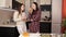 Two young girls chatting in the kitchen and drinking orange juice while dinner is being prepared