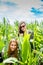 Two young girls hiding in a green cornfield