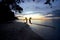 Two young girls jumping by the ocean at sunset