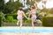 Two Young Girls Jumping Into Swimming Pool Together