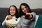 Two young girls looking at the camera pointing with remote control and eat popcorn on a glass bowl