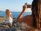 Two young girls make photos on the rocks with phone