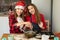 Two young girls are preparing Christmas cookies at home in the kitchen. T