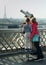 Two young girls stand up to the telescope attempting to gaze at the Eiffel Tower