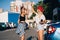 Two young girls in sunglasses posing for the camera on the car parking.