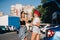 Two young girls in sunglasses posing for the camera on the car parking.