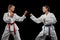 Two young girls, teens, taekwondo athletes training together isolated over dark background. Concept of sport, education