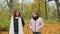 Two young girls walking on fallen yellow leaves in the park rear view.