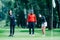 Two young golfers practicing chipping shots on a golf course with golf instructor