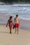 Two young guys walking along the coastline of ocean. Tourism of Asia. Australian and Asian teenagers on the beach.