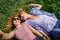 Two young happy woman doing selfie on green grass outdoor. Loving female couple lying face to face on the flowering meadow and