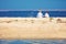 Two young kids, brothers sitting on sandy beach in the morning on the lake coast