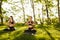 Two young ladies in black sporty tops and leggings sitting in lotus pose and meditating together