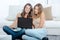 Two young ladies sat on floor looking at laptop