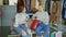 Two young ladies sitting in clothes department in mall and talking after shopping. Colourful women`s garments and