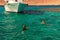 Two young ladies are snorkeling in clean water over reef near the moored yacht. Travel and tourism concept. Red Sea, Dahab, Egypt