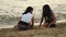 Two young ladies spend summer vacation time on the shore of white sandy beach