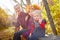 Two young little girl and his mother with blonde hair in an autumn park on a yellow and orange leaf background. Family