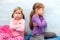 Two young little girls, sisters offended at each other, siblings conflict, fight, taking offence sitting back to back concept