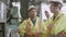 Two young maintenance man in uniform checking on machine and calling with radio phone at industrial factory.