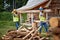 Two young male builders carry timber at cottage construction site in the forest. Construction, building, workers