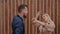 Two young male and female people are dancing outdoors near wooden wall