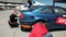Two young male repair blue sports racing car, wheel replacement