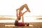 Two young man and beautiful woman on beach doing fitness yoga exercise together. Acroyoga element for strength and