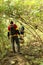 Two Young man hiking in tropical jungle with backpack. Male hiker with rucksack walking along forest trail.