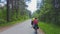 Two young men with backpacks ride bicycles along the road.