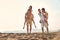 Two young men giving their girlfriends piggyback rides at the beach