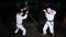 Two young men in kimono training on a parking lot. Sword fight