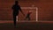 Two young men playing football on the playground at night - one man trying to protect the gates