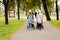 Two young moms girlfriends are walking with young children in strollers for an autumn Park. Women on a walk with the kids, the vie