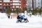 Two young mothers walk with their children in strollers along a winter snow-covered street in a residential area