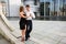 Two young people dancing tango outside on city embankment
