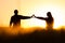 Two young people in love holding hands with shape of heart. Nature scenery, silhouette in rye, wheat field during summer sunrise