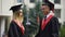 Two young people in mantles communicating before graduation ceremony outdoors