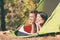 Two young people relaxing in camping tent in summer outdoors nature mountains forest. Happy couple tourists relaxing in