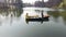 Two young pretty girls sitting in the small boat in the middle of beautiful reflective lake or river. Active lifestyle