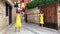 Two young pretty twin sisters violinists in yellow concert dresses are playing electric violins on a small beautiful historical