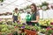 Two young satisfied people watering plants in beautiful garden center