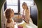 Two young schoolgirls playing shop in a playhouse at an infant school, backlit