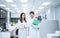 two young scientist in white lab coat standing with automation blood analyzer at medical laboratory