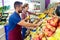 Two young sellers selecting fresh fruit and preparing for working day in fruitshop.