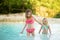 Two young sisters bathing in natural swimming pool in Bagno Vignoni, with thermal spring water and waterfall. Tuscany, Italy