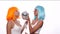 Two young smiling Asian women in bright color wigs posing with photo booth props and small disco ball over white